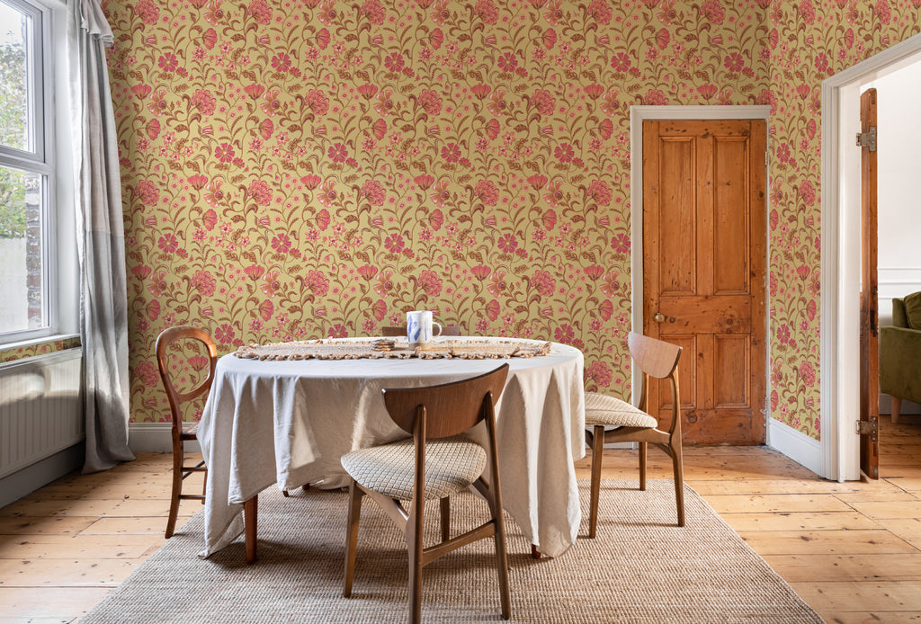 The Pavilion Garland wallpaper in antique gold behind a dining table