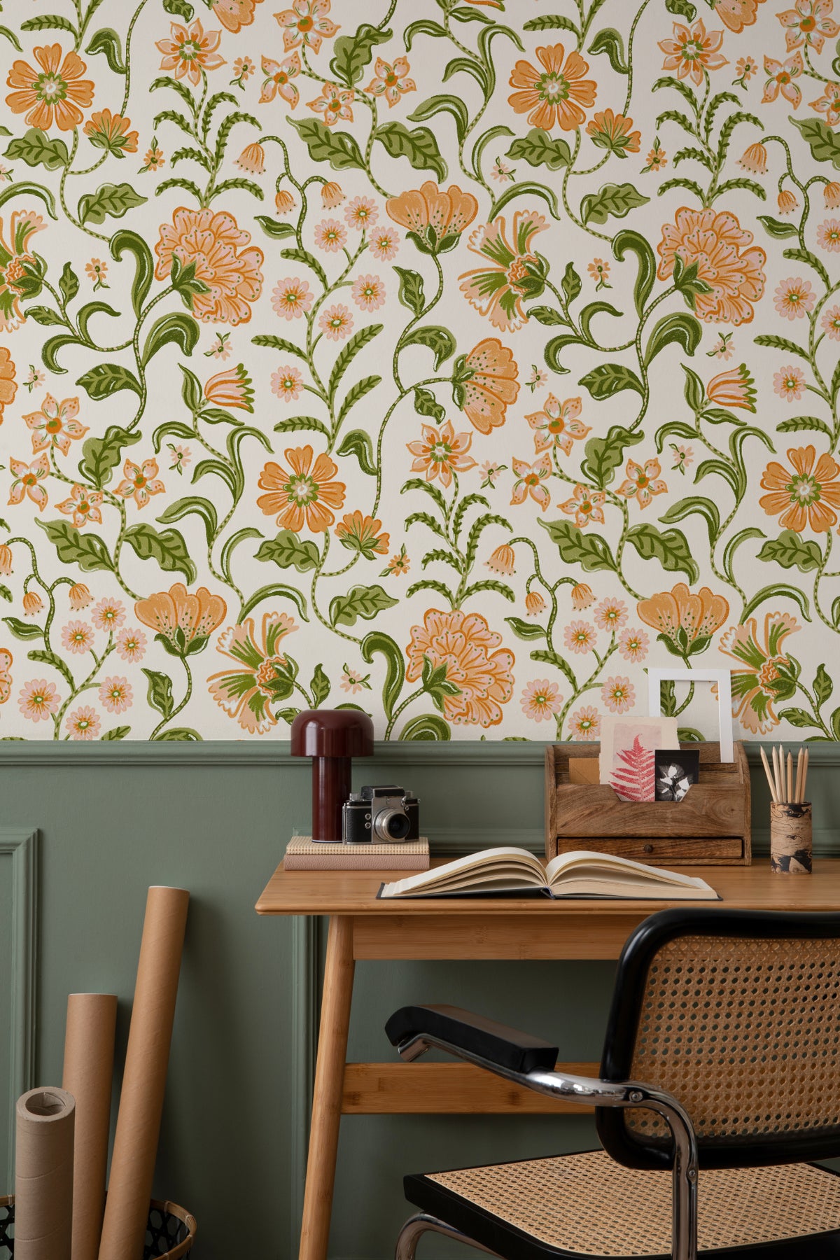 The Pavilion Garland wallpaper in marigold and leaf green behind a desk in a home office