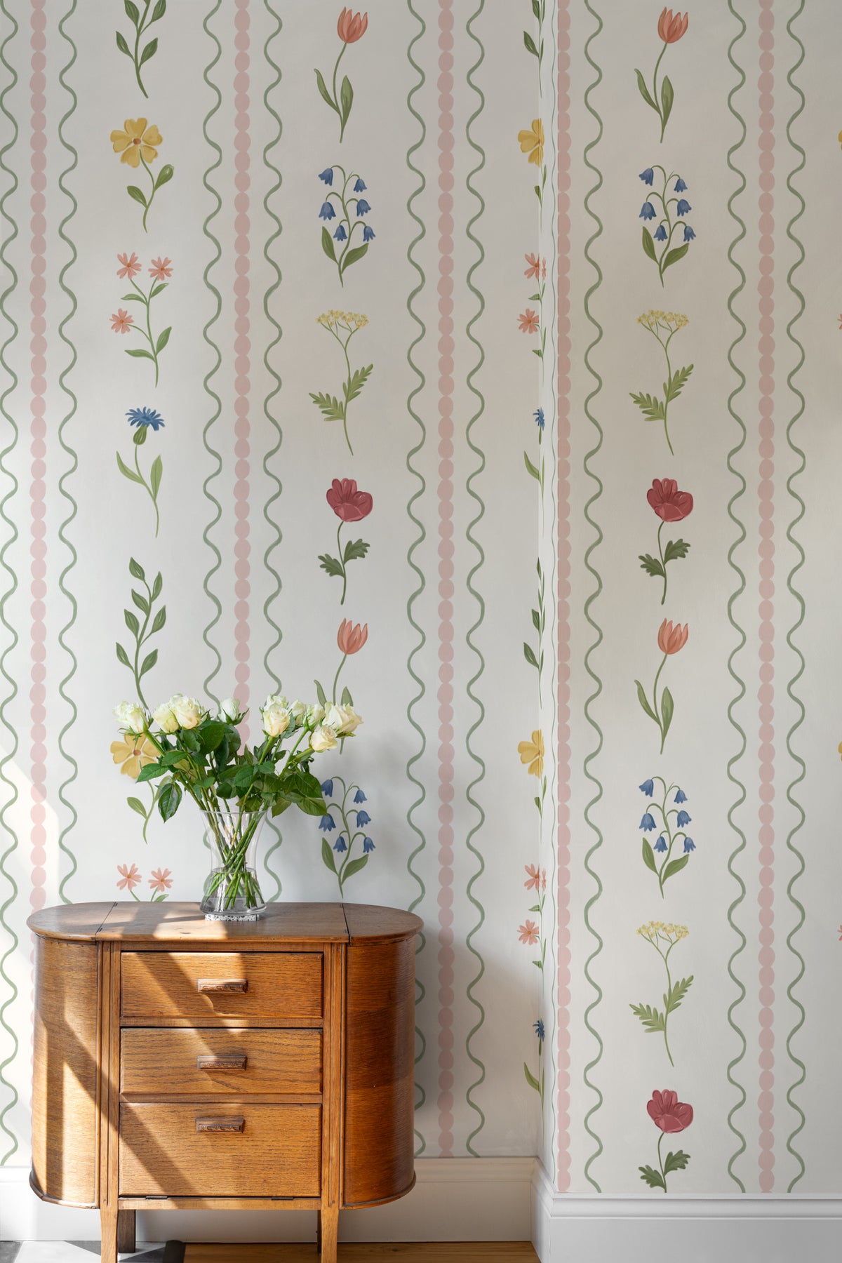 The Posy Braid mural in blush pink behind a styled console