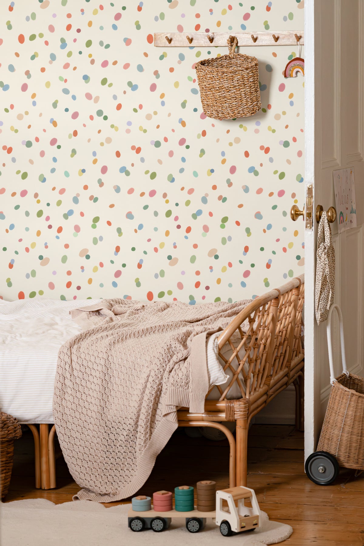 The Sherbet Confetti wallpaper in pastel multi behind the bed in a bedroom