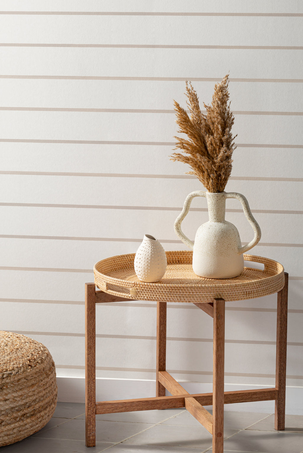 The Shoreline Stripe wallpaper in soft sand behind a styled console