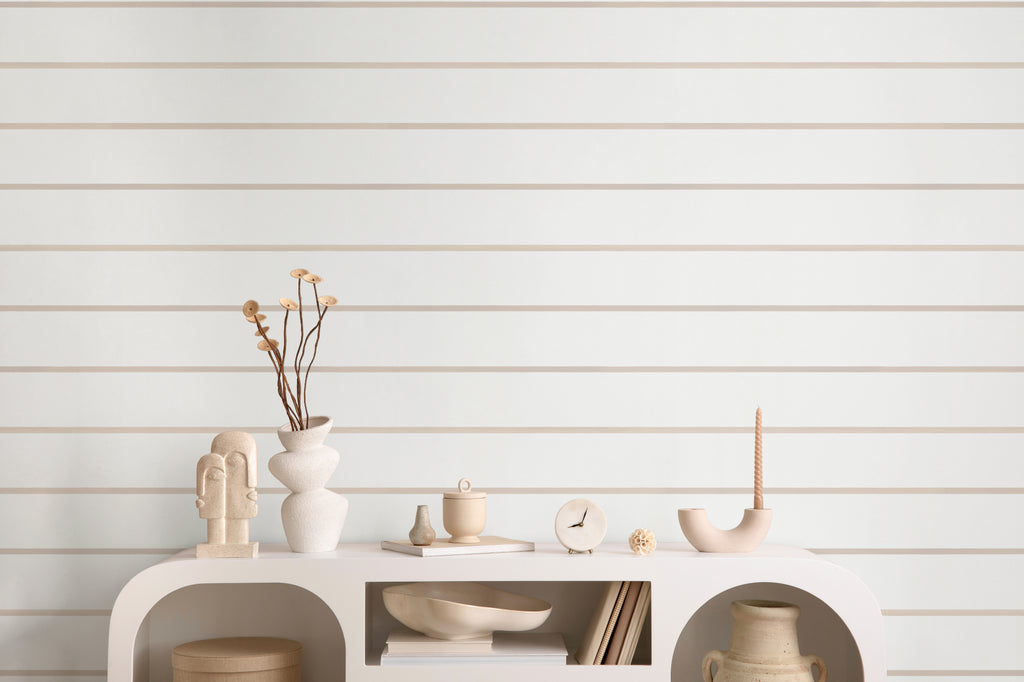 The Shoreline Stripe wallpaper in soft sand as a backdrop to styled furniture