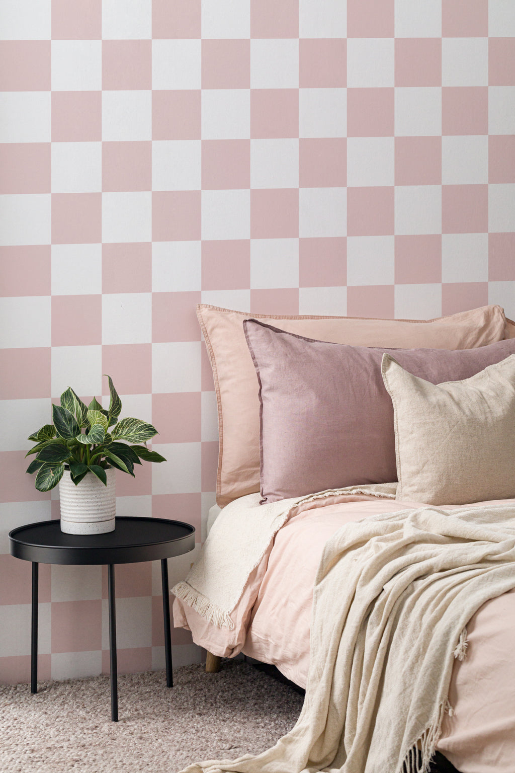 The Sugar Check wallpaper in candy pink and white behind the bed in a bedroom