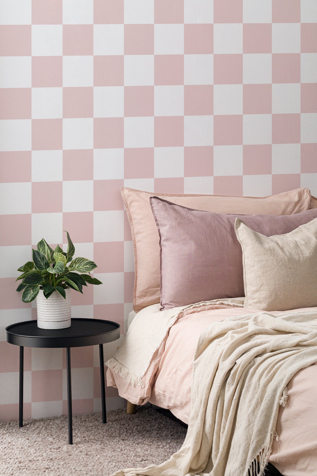 The Sugar Check wallpaper in candy pink and white behind the bed in a bedroom