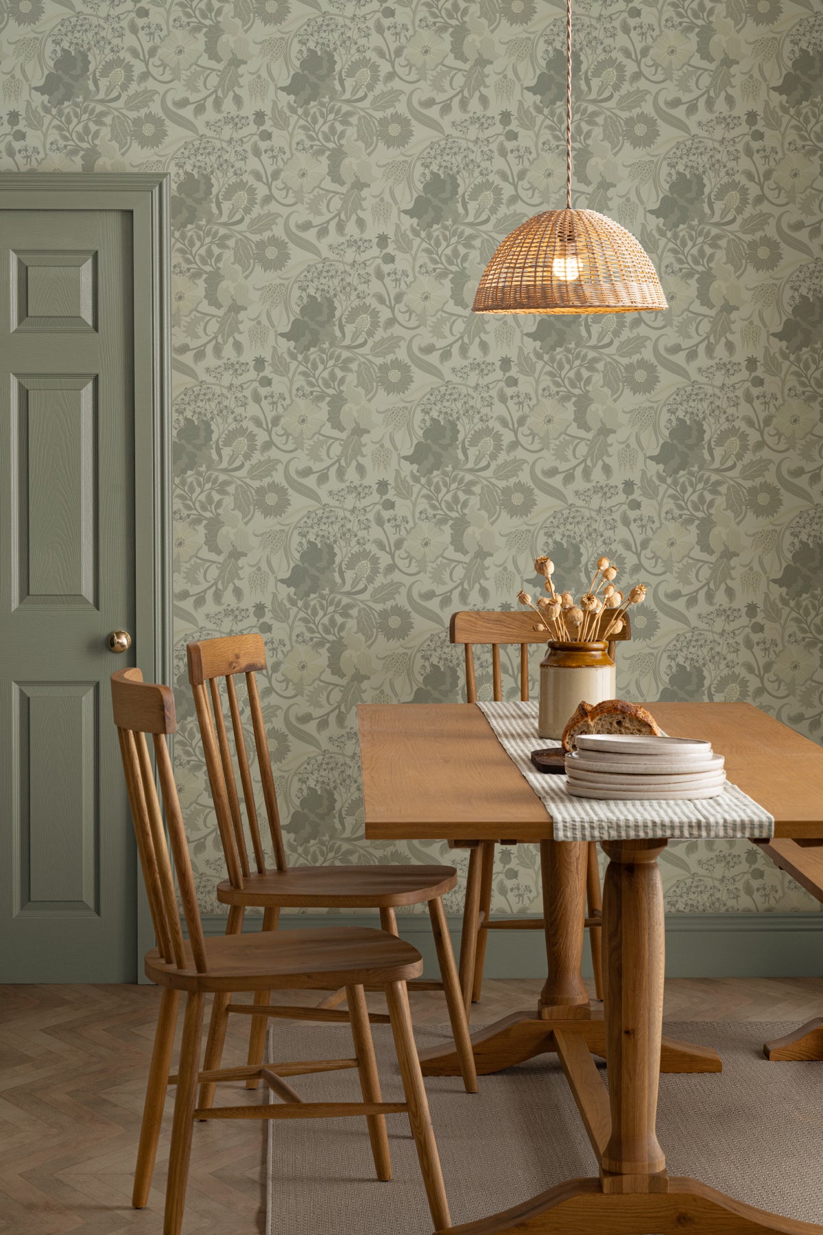 The Thistle Manor wallpaper in sage green behind a dining table