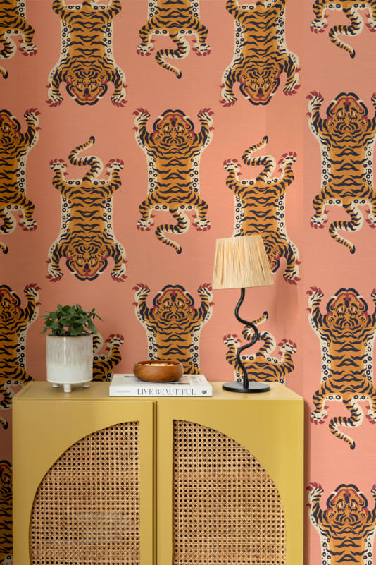 The Tiger Court wallpaper in coral and amber behind a styled console