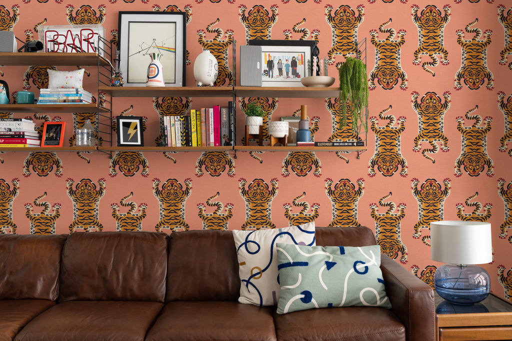 The Tiger Court wallpaper in coral and amber behind seating in a living room