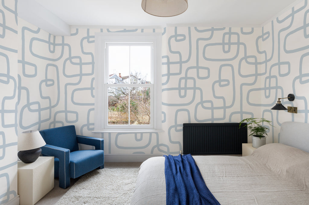The Wandering Line wallpaper in pale blue in a living room