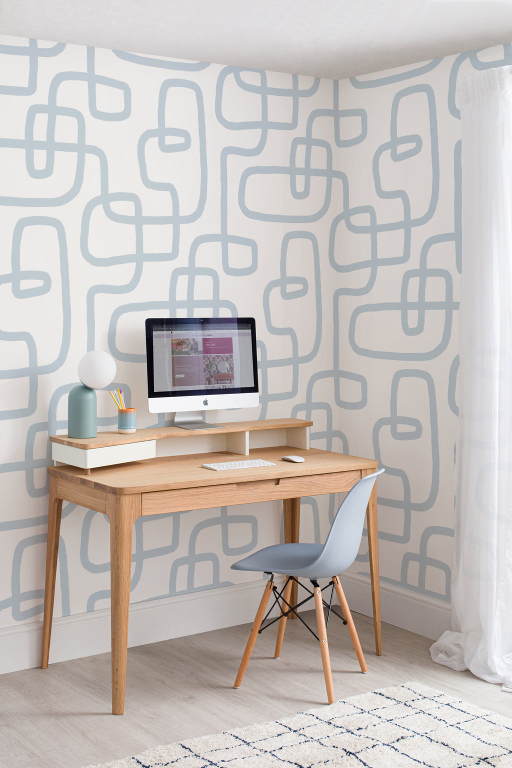The Wandering Line wallpaper in pale blue in a study corner with a desk